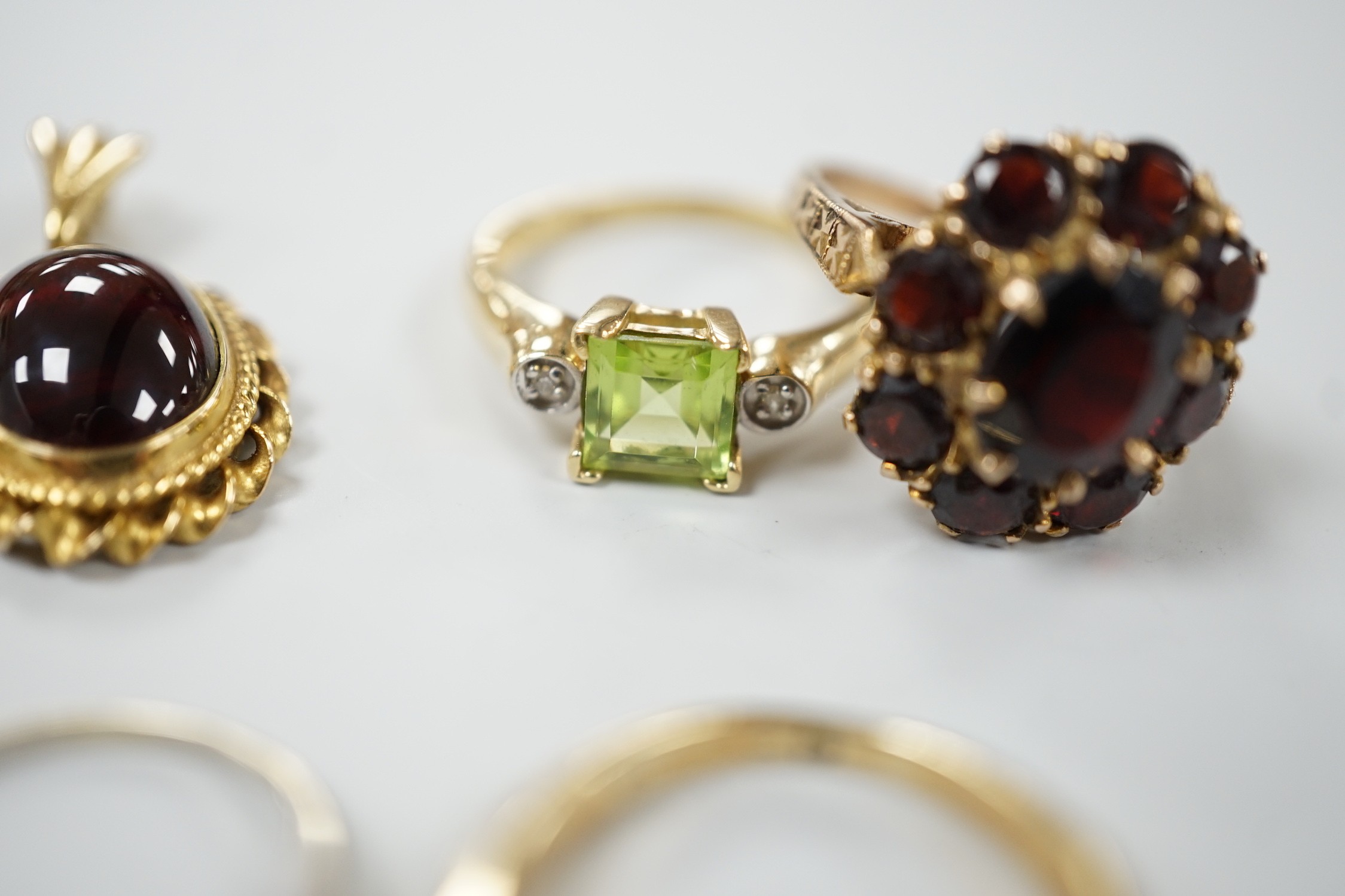 A 9ct and garner cluster set dress ring, size M, gross 4.9 grams, two yellow or white metal and diamond set rings, including half eternity and a yellow metal and garnet set half hoop ring, gross 8.8 grams, a 14k, single